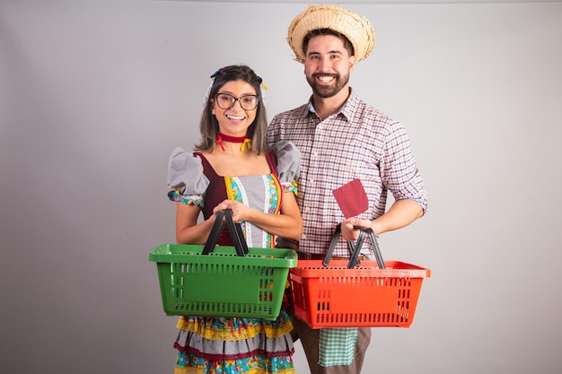 Pareja brasileña vestida con ropa de festa junina fiesta de Sao Joao con cesta de compras del supermercado