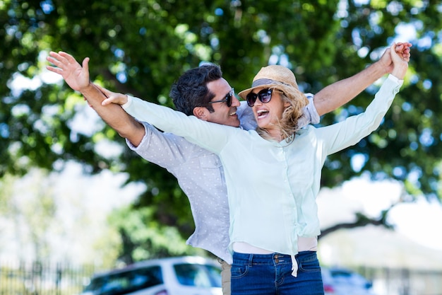 Pareja con los brazos extendidos contra los árboles