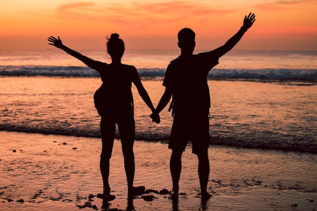 Pareja con los brazos levantados en una playa