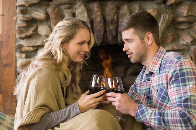 Pareja brindando copas frente a la chimenea encendida