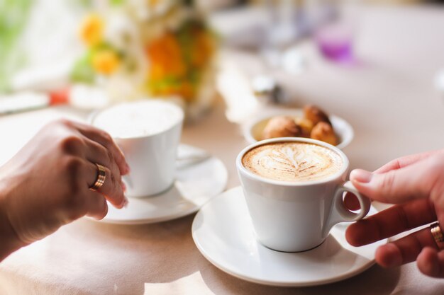 Pareja en café, sosteniendo una taza de café