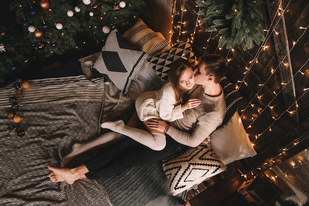 Pareja en la cama en el dormitorio oscuro interior año nuevo y navidad abrazos y besos amor blanco sw ...