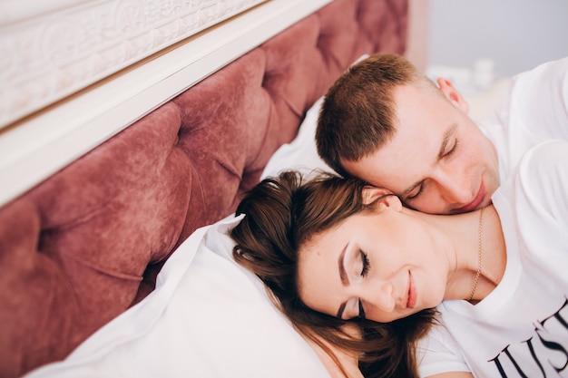 Pareja en la cama feliz niña y novio debajo de las sábanas.