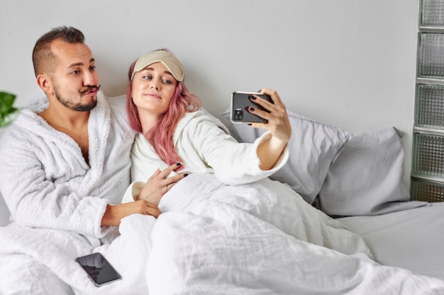 Pareja en la cama tomar una foto en el teléfono inteligente