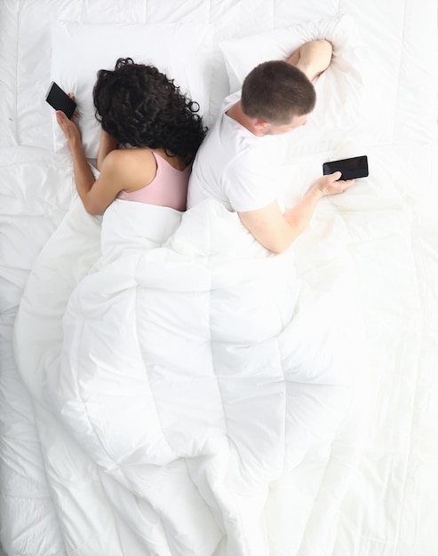 pareja, en cama, utilizar, teléfonos, acostado, espaldas, uno al otro