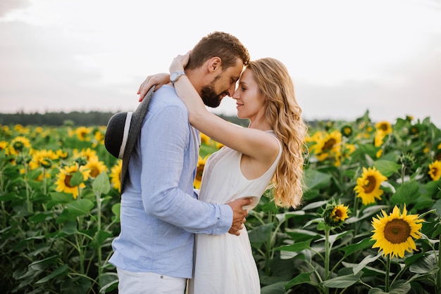 Pareja camina en los girasoles en un campo en un día de verano