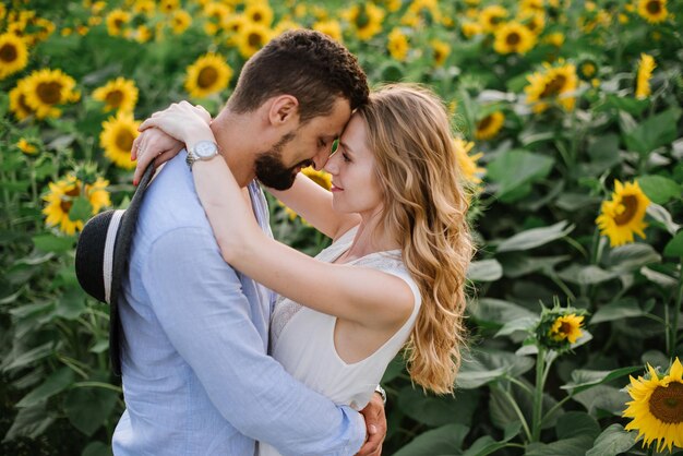 Pareja camina en los girasoles en un campo en un día de verano