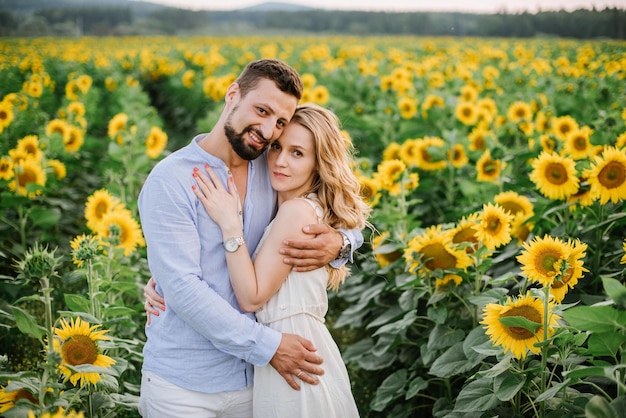 Pareja camina en los girasoles en un campo en un día de verano