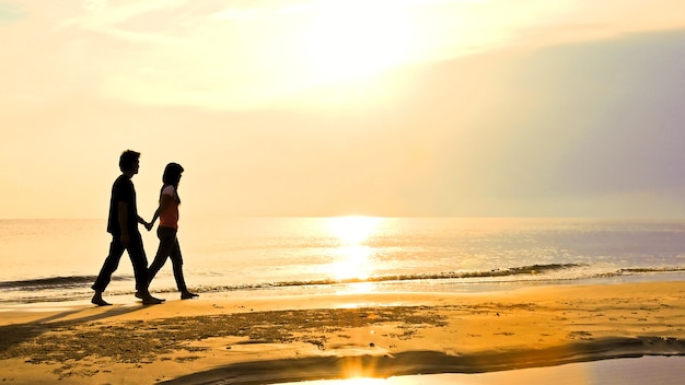 Foto pareja camina juntos en la playa al atardecer, huahin, tailandia