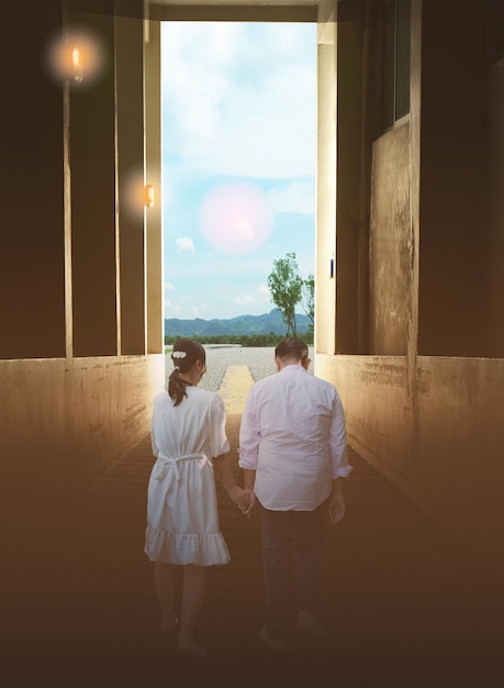 Una pareja camina de la mano en un túnel con focos al costado de la carretera donde hay un camino con árboles y un cielo brillante Los hombres y mujeres se animaron mutuamente a seguir caminando