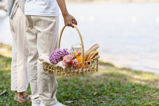 Pareja caminando en el jardín con una cesta de picnic enamorada pareja está disfrutando de un picnic en el parque al aire libre