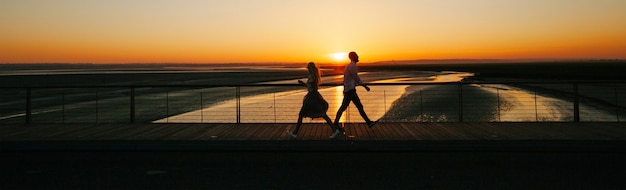 Pareja caminando junto a un río durante la puesta de sol