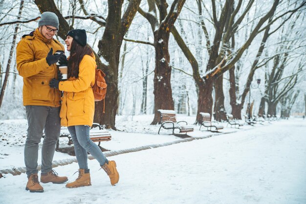 Pareja caminando por el parque de la ciudad nevada hablando socializando una cita romántica en invierno