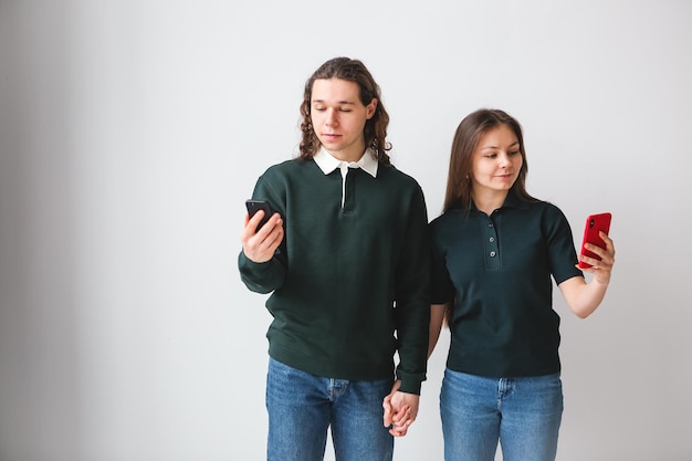 Foto pareja en camisas verdes con teléfonos en las manos sobre fondo blanco hombre y mujer joven usando teléfonos