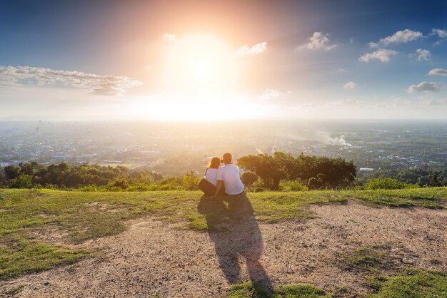 Pareja con camiseta blanca sentado en el punto de vista en el momento de la puesta del sol.