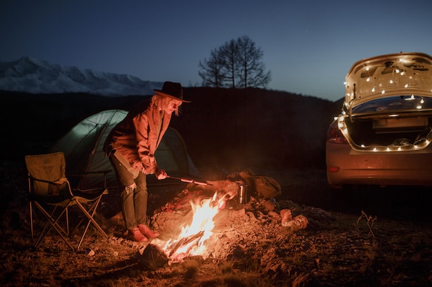 Pareja en camping con fogata en la noche en las montañas