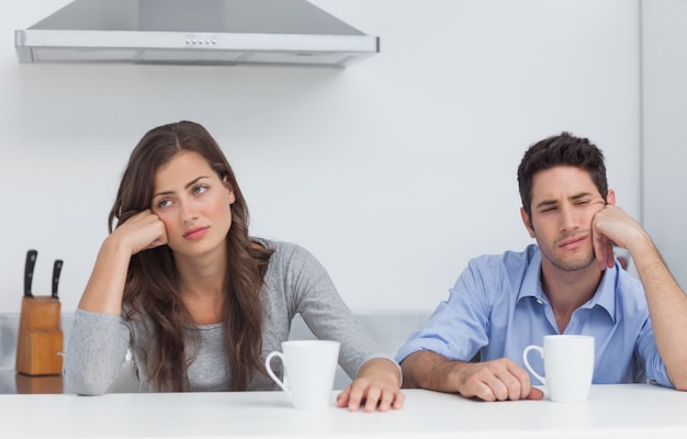 Pareja cansada sentada en la mesa con una taza de café