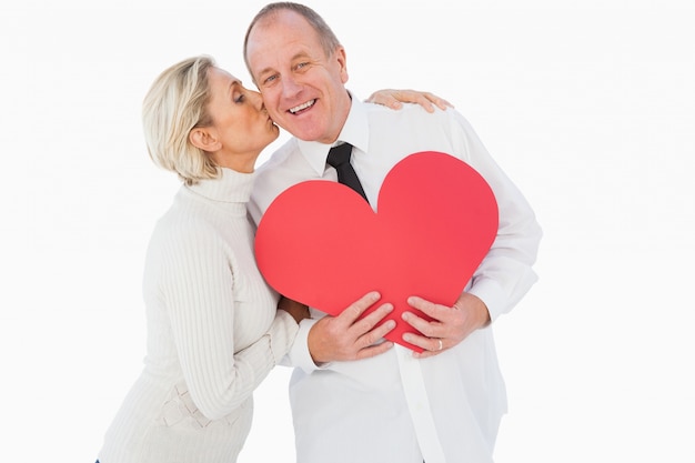 Pareja cariñosa mayor sosteniendo forma de corazón rojo