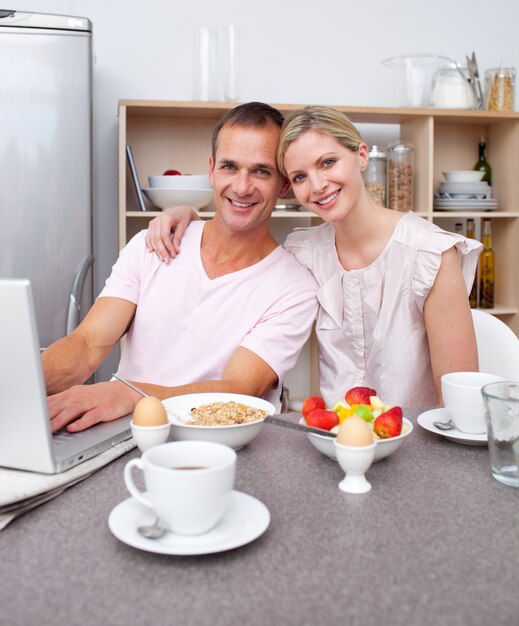 Pareja cariñosa usando una laptop mientras desayunando