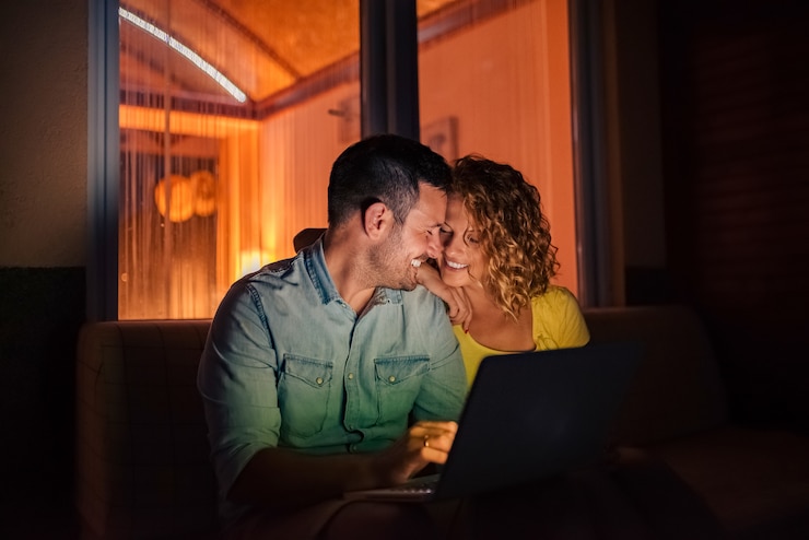 Foto pareja cariñosa usando laptop en la noche.