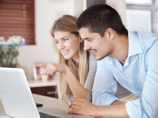 Pareja en casa y computadora para leer noticias planificación y compras en línea en la cocina con elección mujer y hombre en portátil con software de comercio electrónico o sitio web para registro de información y suscribirse