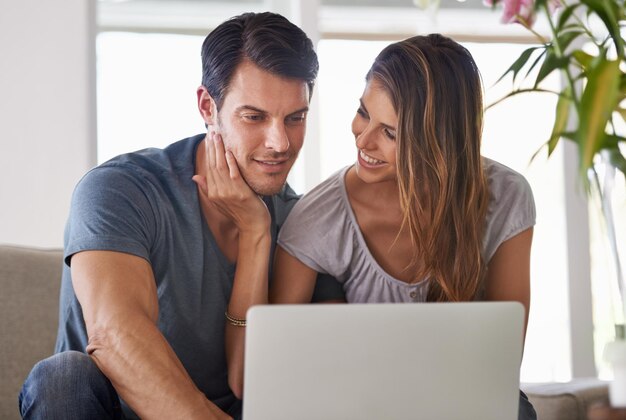 Pareja casa y portátil para el entretenimiento sonrisa y amor para el abrazo y el afecto en el sofá en el salón hombre mujer y sentarse con la novia tecnología y computadora en la sala de estar para relajarse y ser feliz
