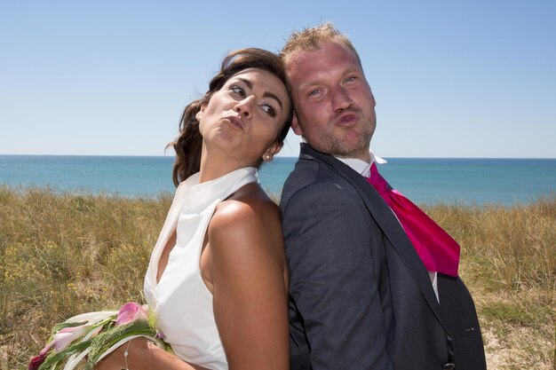 Pareja casada alegre de pie en la playa