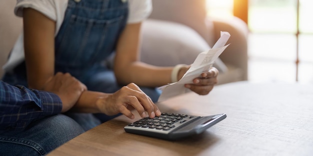 Foto una pareja casada se sienta en el sofá, lee documentos financieros, facturas, problemas con gastos demasiado altos, costos de servicios públicos, jóvenes cónyuges preocupados por la deuda, bancarrota del negocio de contabilidad familiar.