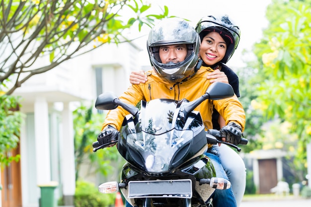 Pareja con cascos montando motocicleta