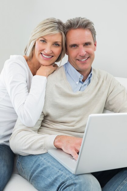 Pareja casual feliz usando laptop en casa