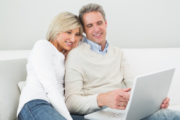 Pareja casual feliz usando laptop en casa