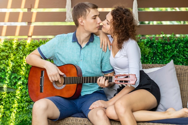 Pareja caucásica tocando la guitarra acústica de su amada chica.