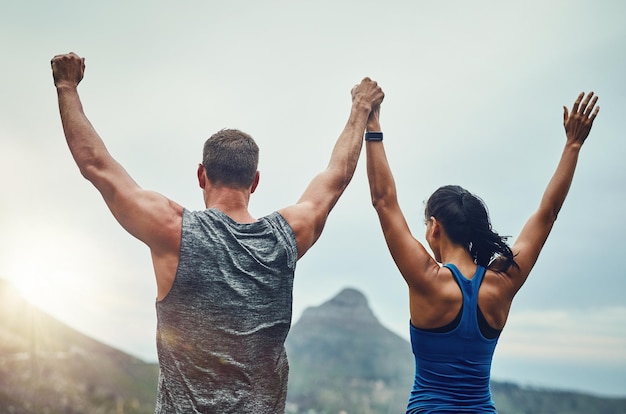 Foto pareja celebración y brazos arriba en la naturaleza para entrenar o hacer ejercicio para correr una competencia de maratón o un torneo gente ganadora y feliz por el objetivo o logro de los deportes de libertad