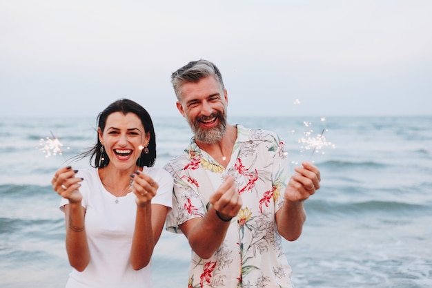 Pareja celebrando con bengalas en la playa