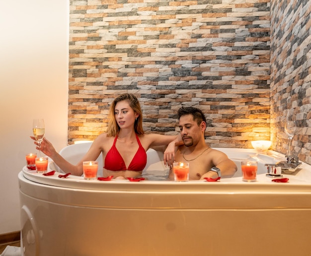 Pareja celebrando una velada romántica por San Valentín en un hotel con jacuzzi.