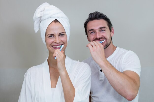 Pareja cepillarse los dientes en el baño.