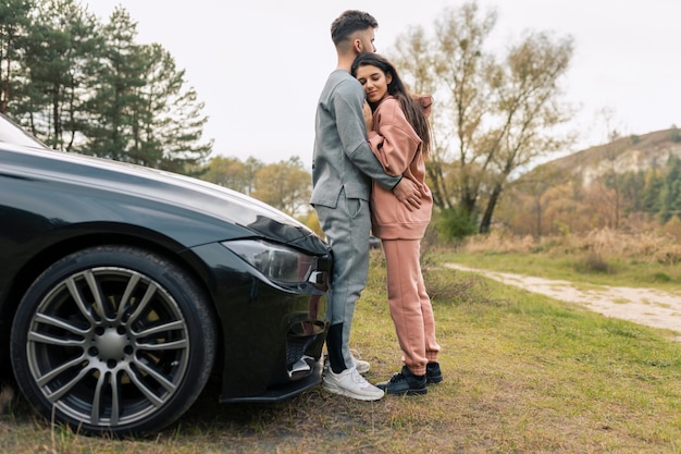 Pareja cerca del coche en la naturaleza