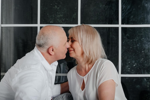 pareja cerca de la ventana abrazándose, besándose y sonriendo