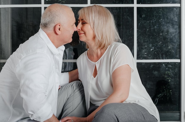 pareja cerca de la ventana abrazándose, besándose y sonriendo