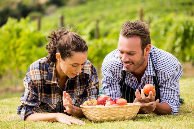 Pareja con cesta de manzana en viñedo