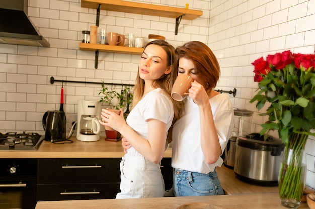 Pareja de chicas abrazándose en la cocina en el día de San Valentín y tomando café