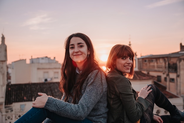 Pareja de chicas jóvenes celebrando el amor en una puesta de sol