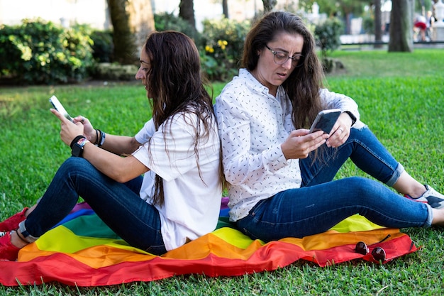 Pareja de chicas lesbianas con una bandera del orgullo LGBT sentada en la p