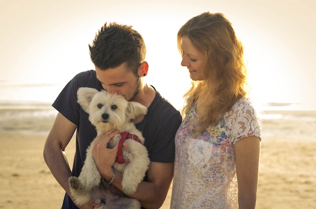 Pareja de chicos jugando con su perro en la playa