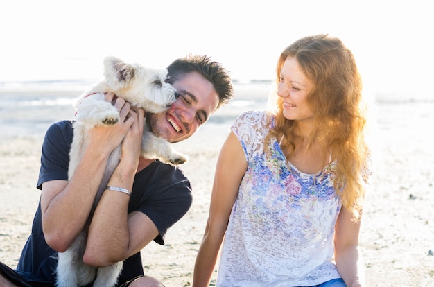 Pareja de chicos jugando con su perro en la playa