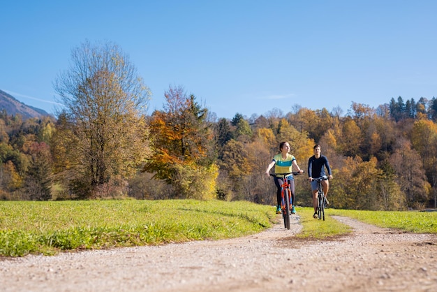 Pareja de ciclistas recreativos disfrutando del paisaje de una zona rural mientras montan bicicletas en el país