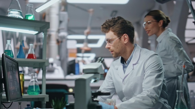 Una pareja de científicos trabajando en un laboratorio moderno cerca de sus colegas de laboratorio sonrientes
