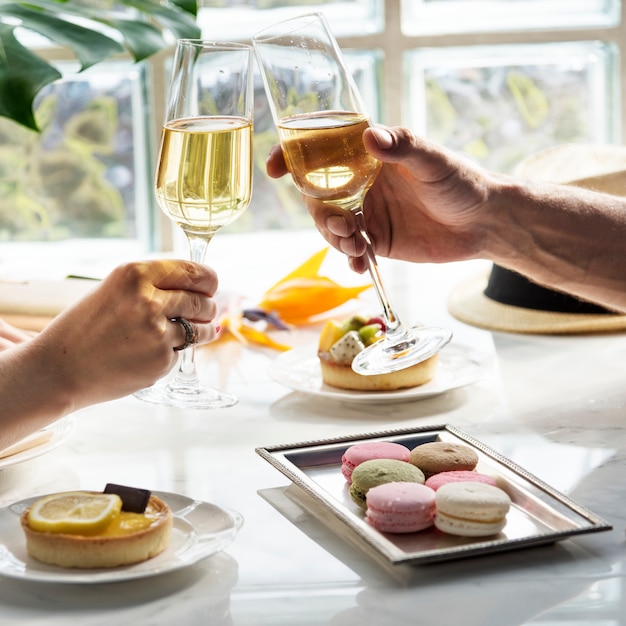 Una pareja en una cita levantando copas de champán y comiendo postres en un restaurante