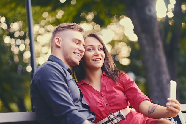 Una pareja en una cita en un parque de la ciudad usando un teléfono inteligente y mensajería instantánea.