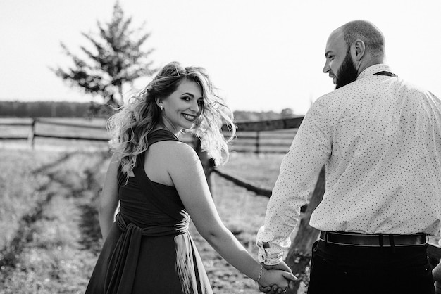 Foto pareja en una cita. vestido morado. la novia y el novio. camina por el campo. historia de amor. fotografía en blanco y negro.